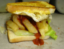 A TOASTED SANDWICH WITH CHEESE, EGG AND CHIPS COVERED IN SPICE AND SAUCE